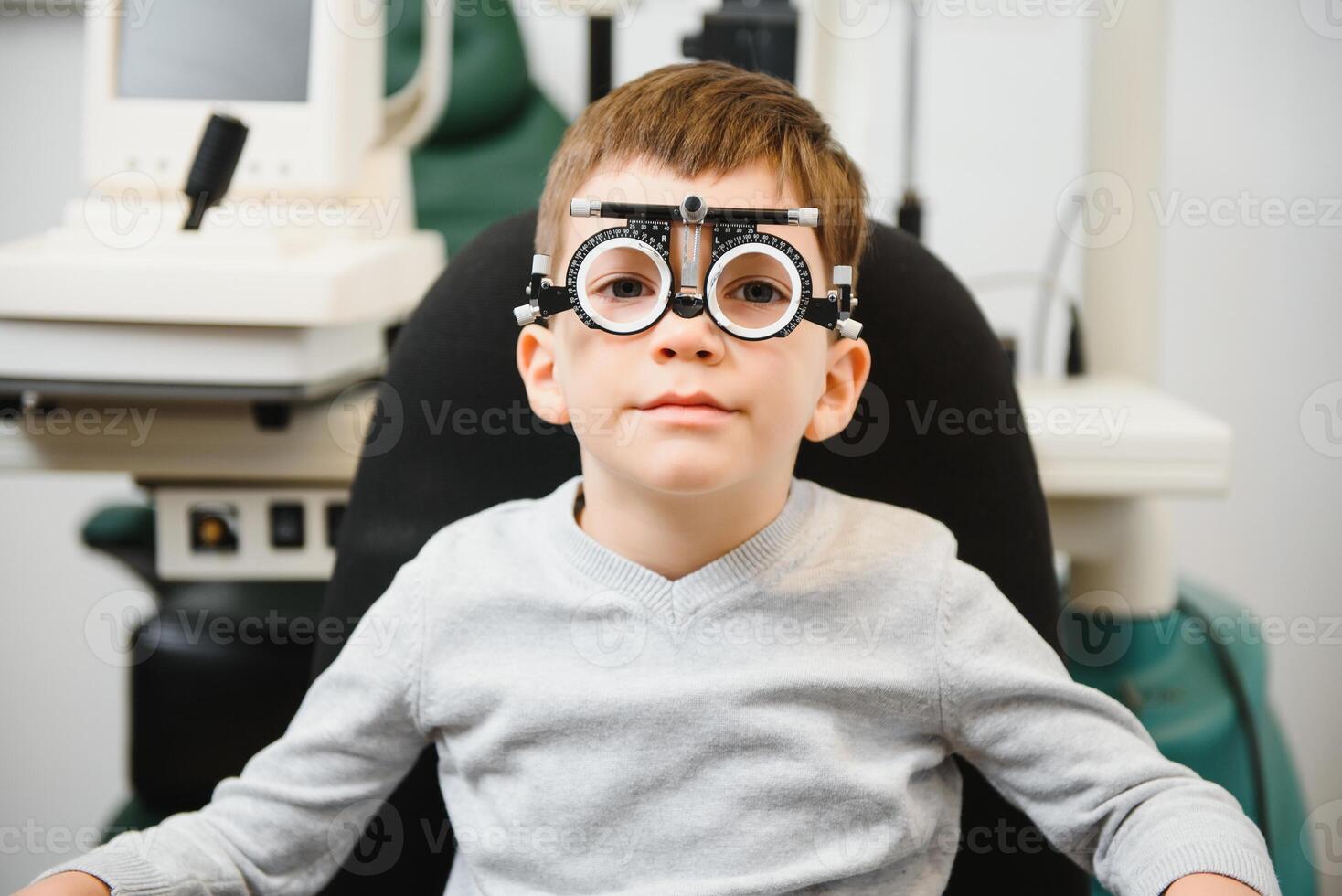 Jeune garçon subissant œil tester avec lunettes dans médical clinique. photo
