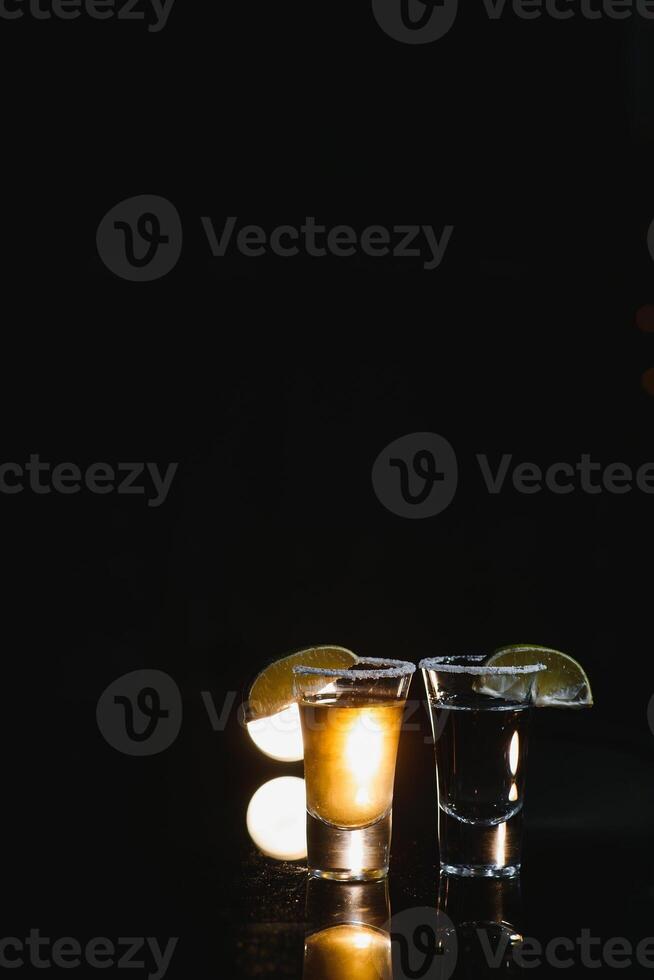 savoureux de l'alcool boisson cocktail Tequila avec citron vert et sel sur vibrant foncé Contexte. fermer. photo
