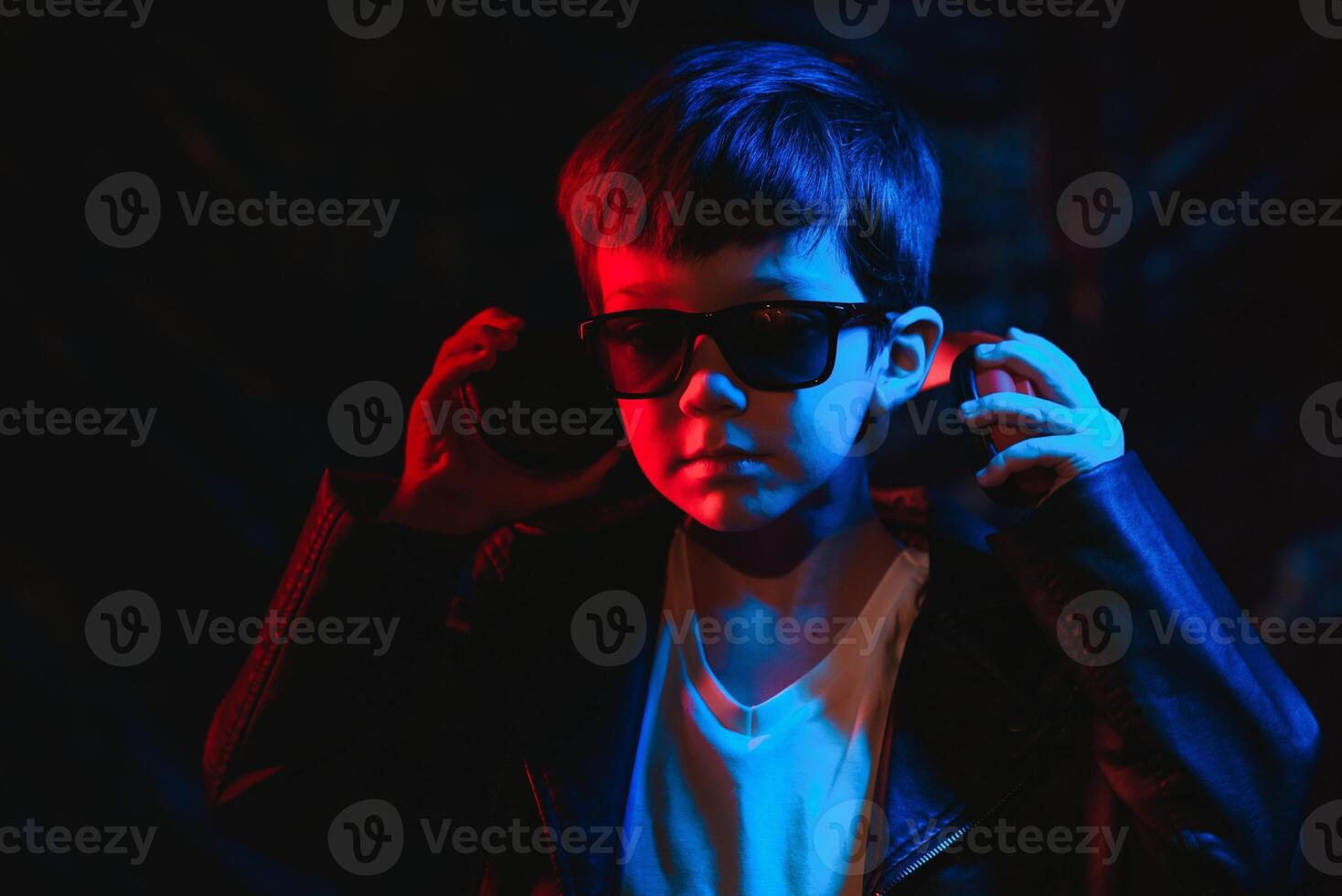 studio coup dans foncé studio avec néon lumière. portrait de une élégant garçon avec écouteurs photo