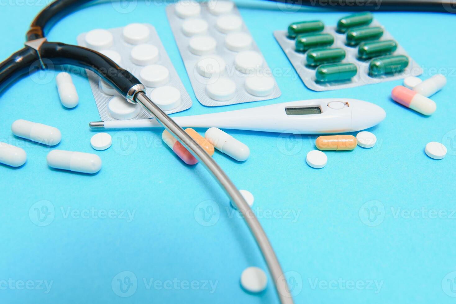 épars blanc pilules sur bleu table.médicale, pharmacie et soins de santé concept. bleu Contexte blanc pilules avec une médical statoscope, Haut vue photo
