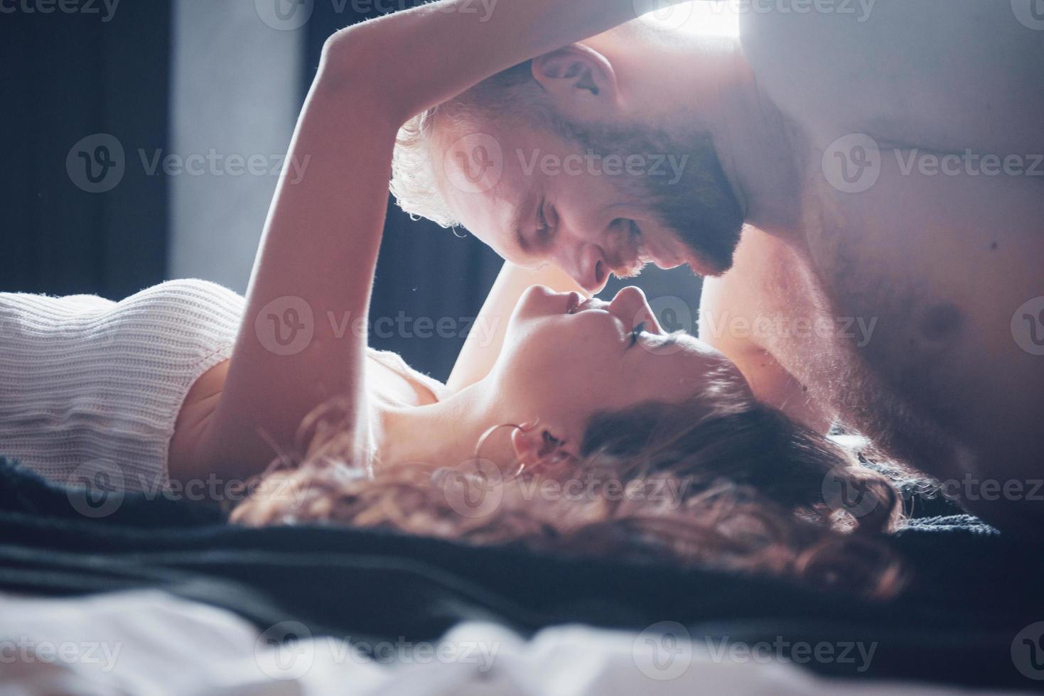 un portrait d'un jeune couple heureux qui se détend dans un lit douillet photo