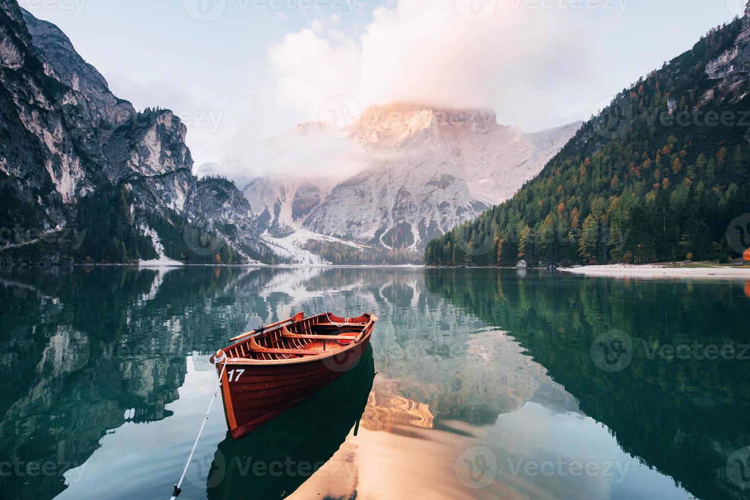 bel environnement. bateau en bois sur le lac de cristal avec une montagne majestueuse derrière. reflet dans l'eau photo