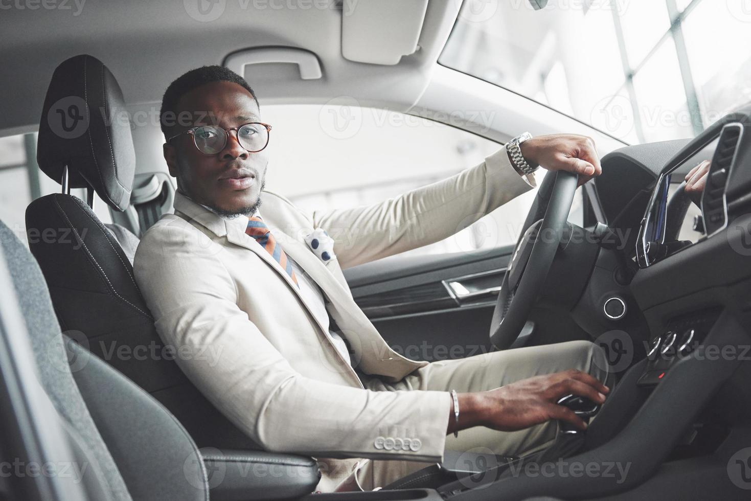 homme d'affaires noir élégant assis au volant d'une nouvelle voiture de luxe. riche afro-américain photo