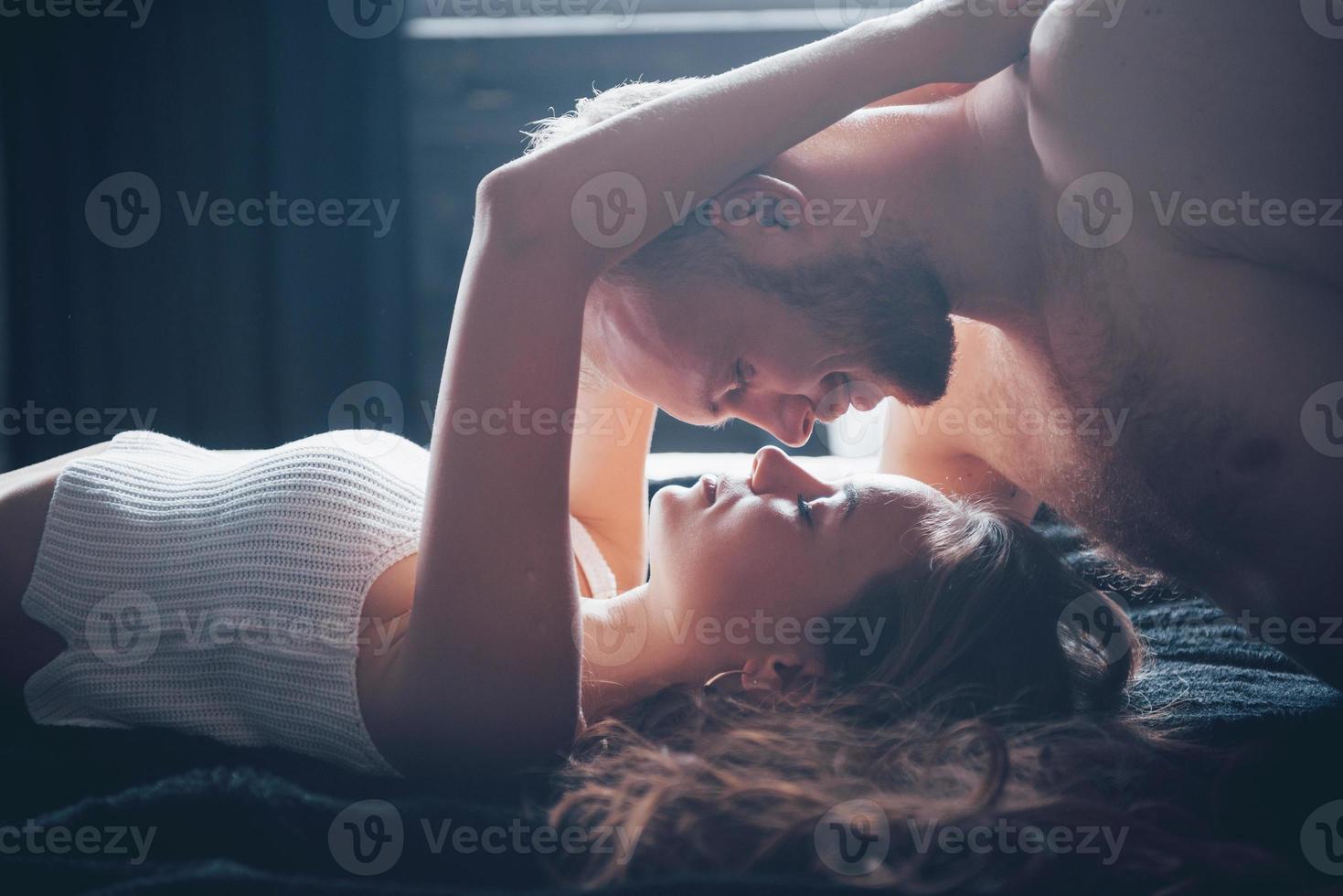 un portrait d'un jeune couple heureux qui se détend dans un lit douillet photo