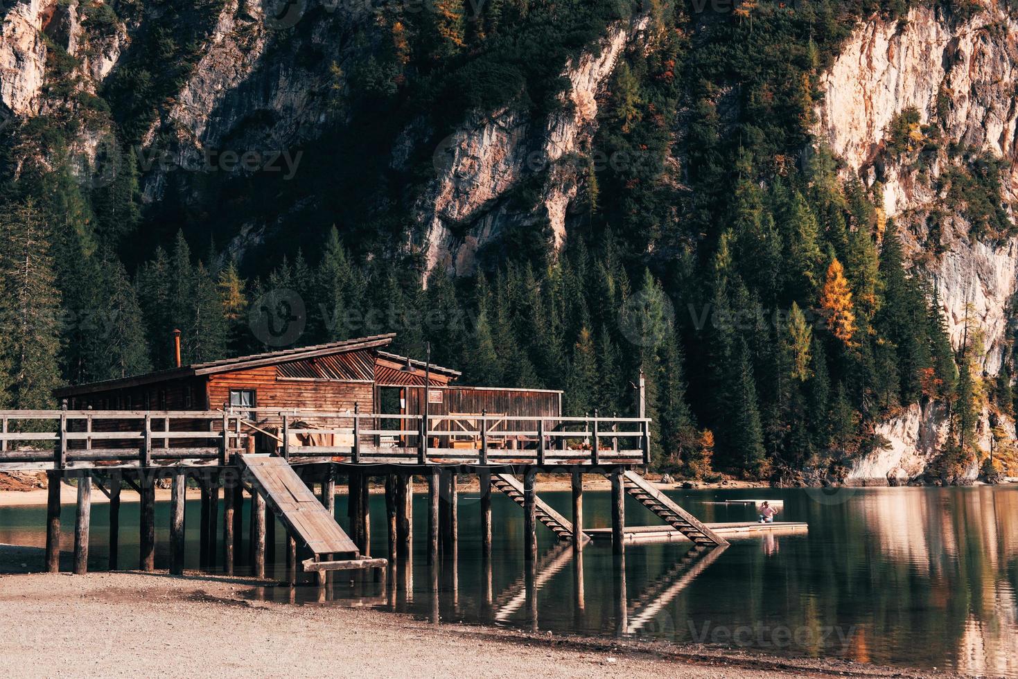 fille est assise au bord de l'embarcadère et prend un selfie. lieu touristique avec bâtiment en bois et poire photo