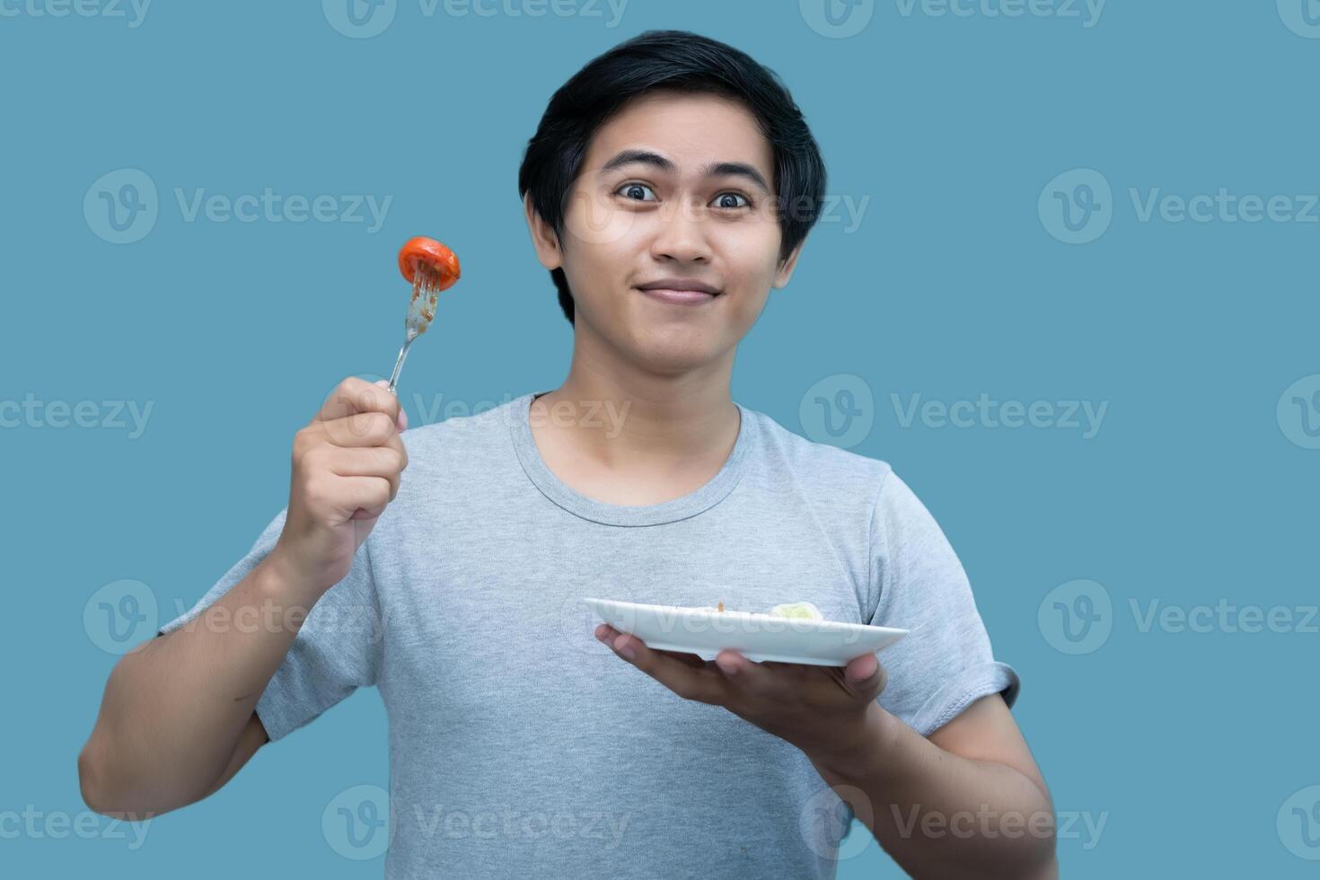 une homme dans une gris chemise est en portant une fourchette et une assiette contenant nourriture, pour conception et visuel édition fins. photo