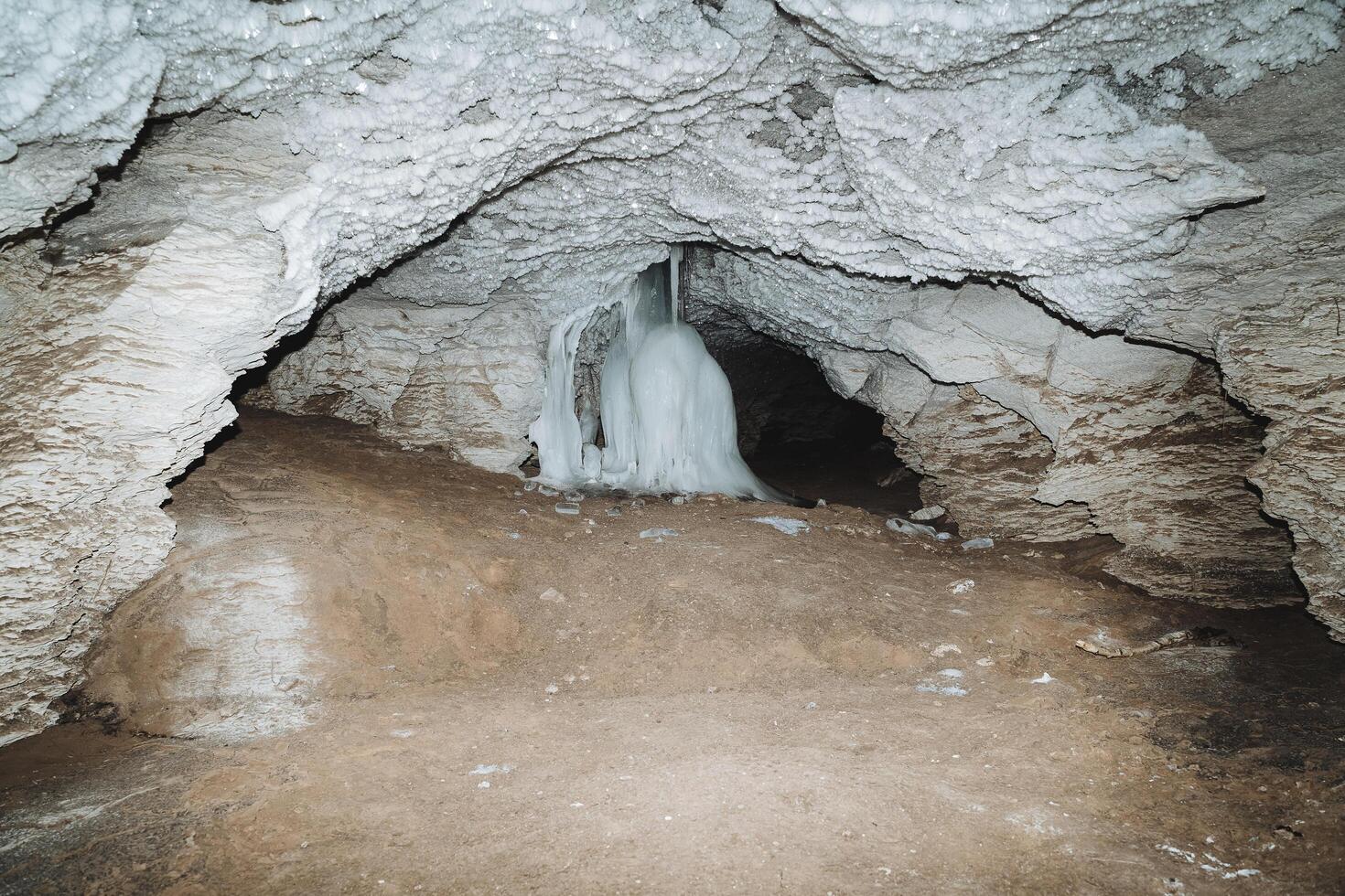 la grotte Karlamanskaya Russie Bachkortostan du sud Oural, karst salle de le la grotte est illuminé par le lumière de une lanterne, la glace les flux vers le bas le mur, spéléologie photo