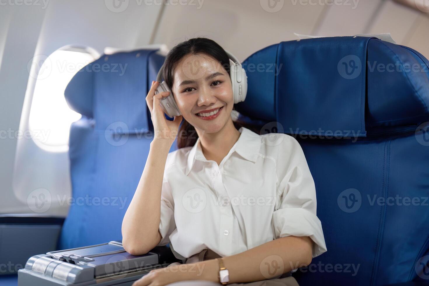 asiatique Jeune femme portant casque de musique Ecoutez à la musique à premier classe sur avion pendant vol, en voyageant et affaires concept photo