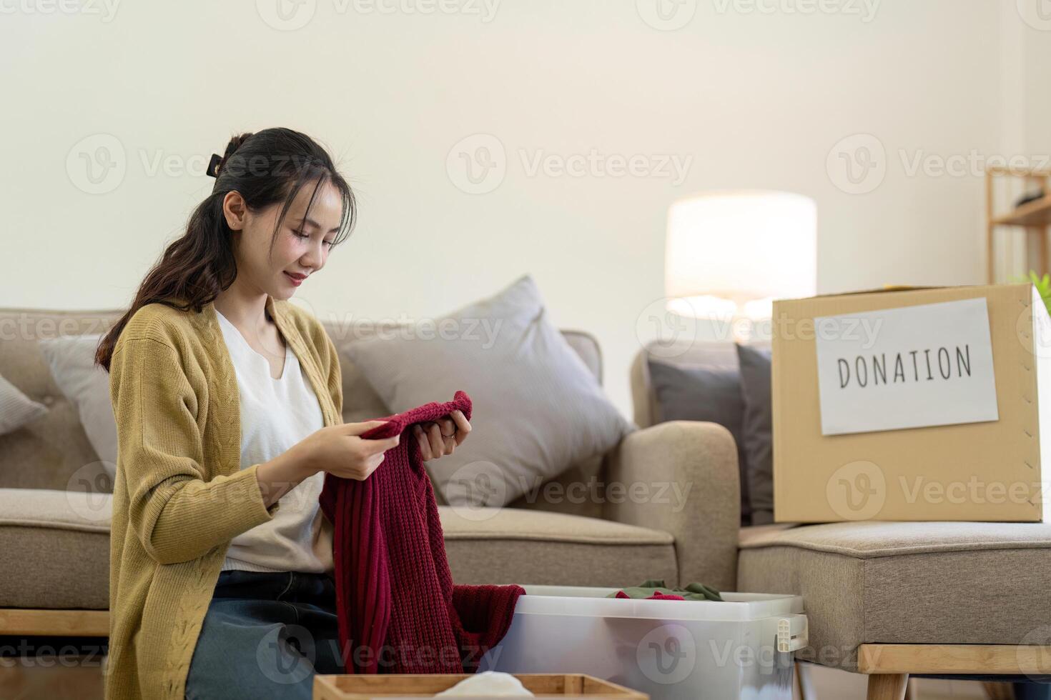 femme asiatique en portant don boîte plein avec vêtements et sélectionner vêtements. concept de don et vêtements recyclage. portion pauvres gens photo