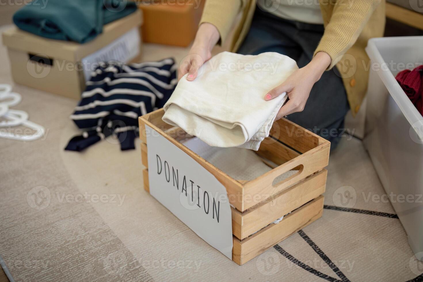 don, asiatique Jeune femme séance pack objet à maison, en mettant sur des trucs dans faire un don boîte avec seconde main vêtements, charité portion et nécessiteux personnes. réutilisation recycler photo