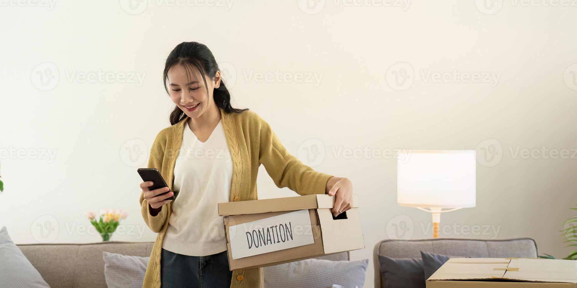 don concept. femme asiatique en portant une faire un don boîte avec plein de vêtements. femme en portant vêtements faire un don boîte. vêtements dans boîte pour concept don et réutilisation recycler photo