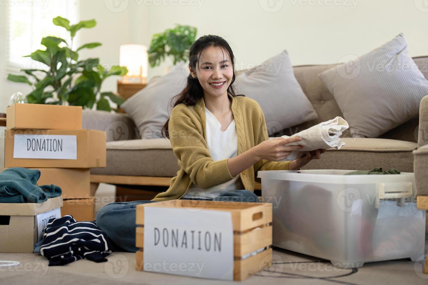 femme asiatique en portant don boîte plein avec vêtements et sélectionner vêtements. concept de don et vêtements recyclage. portion pauvres gens photo