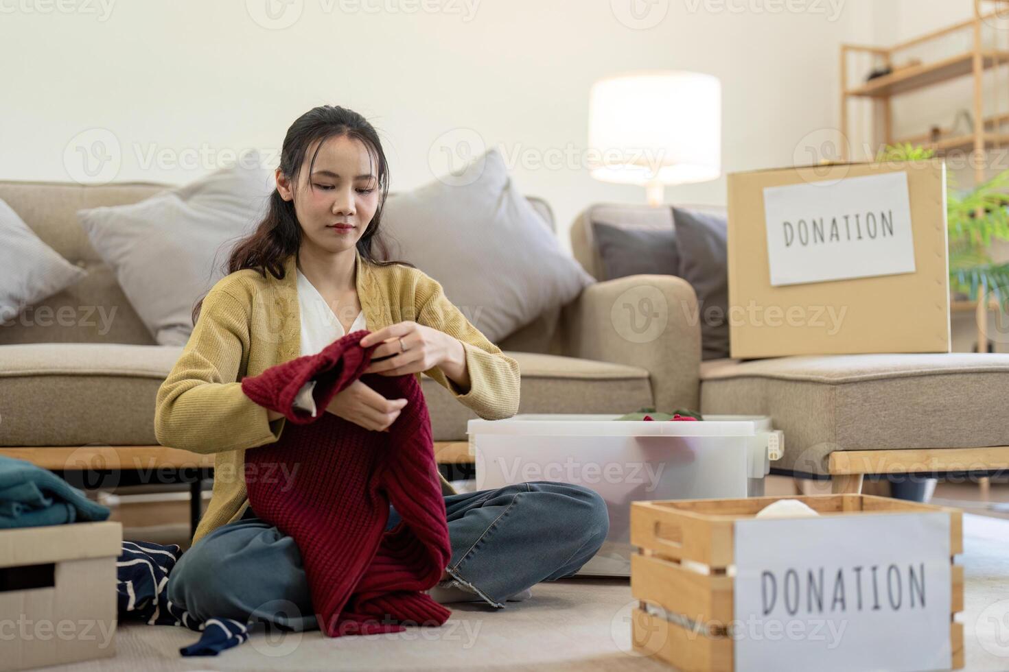 femme asiatique en portant don boîte plein avec vêtements et sélectionner vêtements. concept de don et vêtements recyclage. portion pauvres gens photo