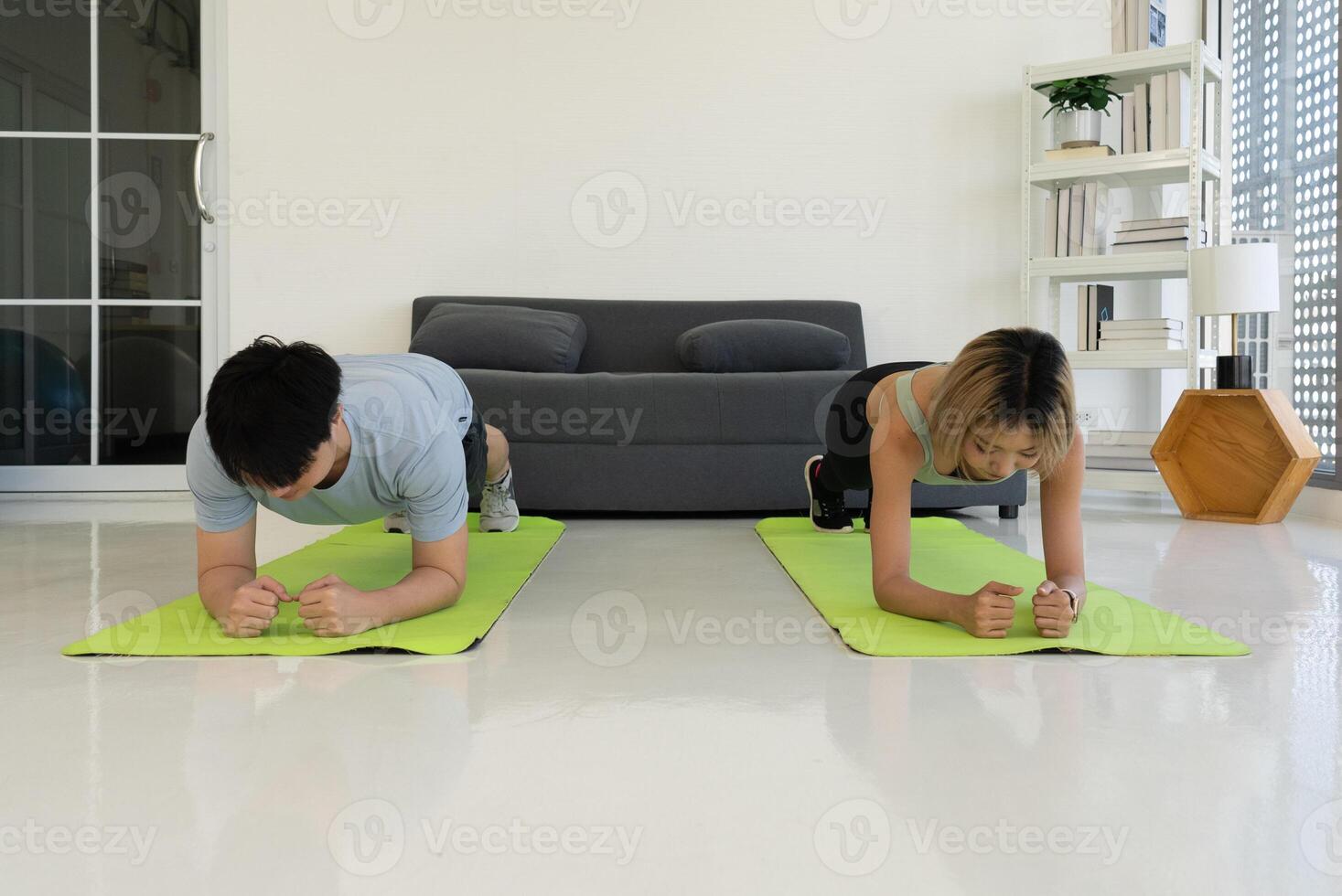 Jeune asiatique couple faire des exercices à Accueil par Faire planche photo