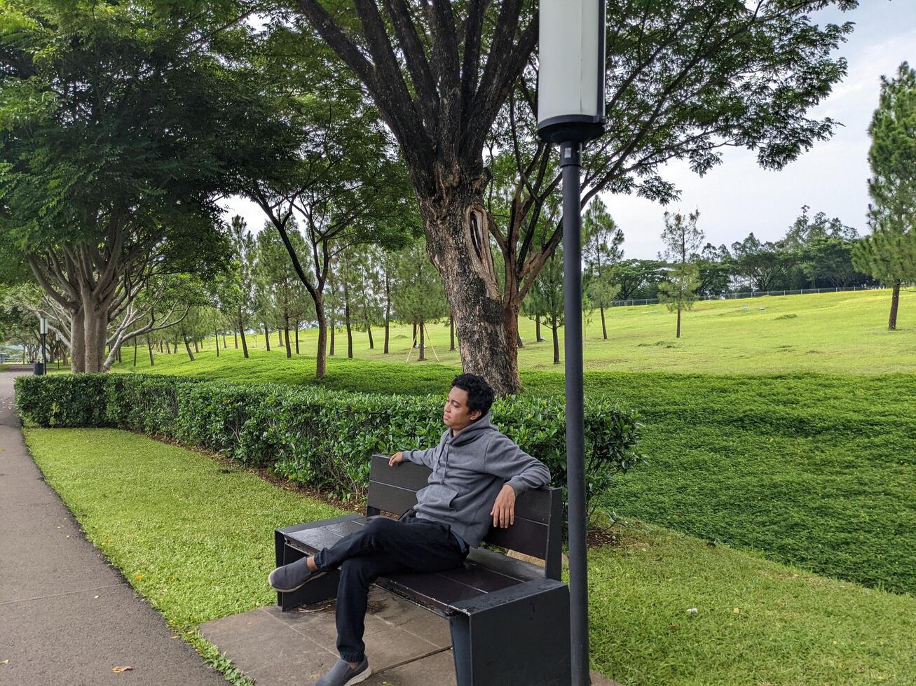 homme asseoir sur le vert parc vers le bas ville. le photo est adapté à utilisation pour calme apprécié activité, loisir activité et parc Contexte.