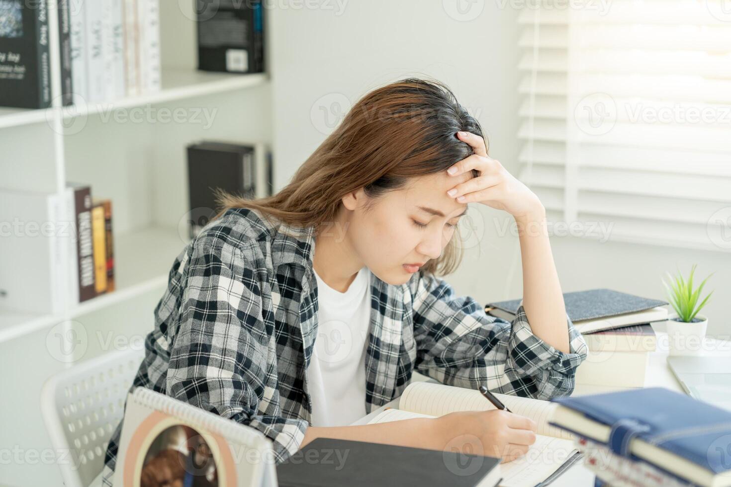 une étudiante asiatique a de l'anxiété à cause des examens, les femmes se préparent aux tests et apprennent les leçons à la bibliothèque. stress, désespoir, hâte, incompréhension lecture, découragement, attente, connaissance photo