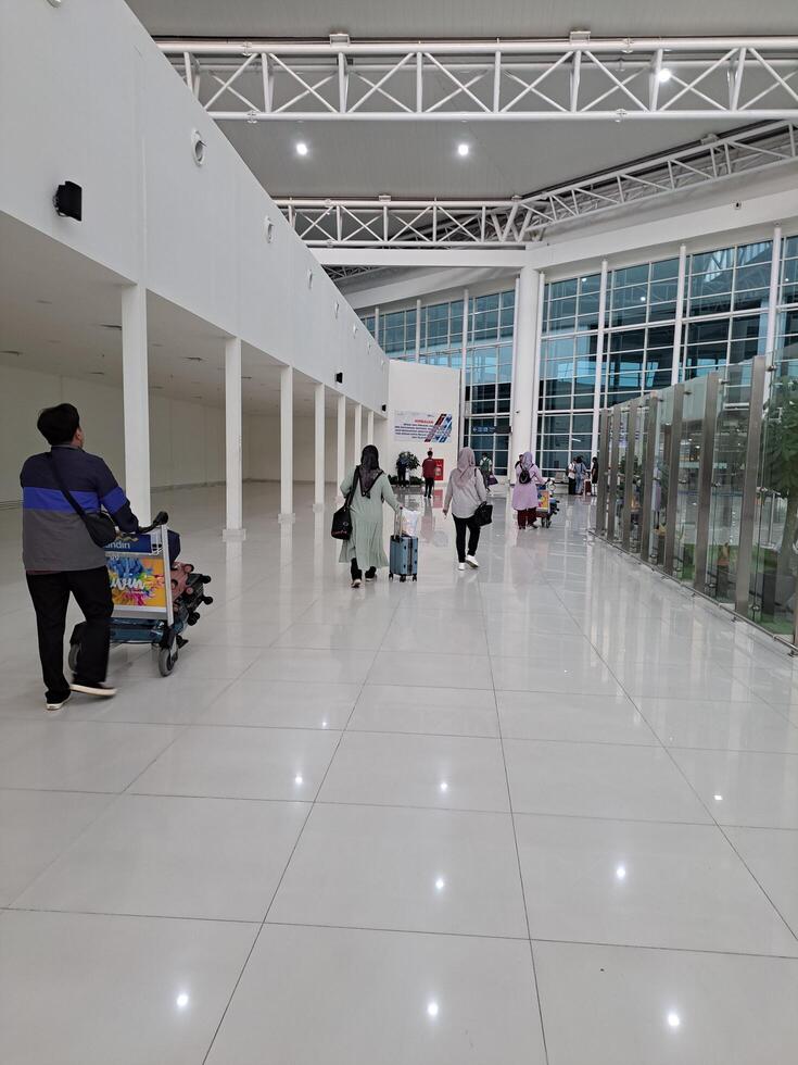 Banjarbaru, Indonésie - janvier 29e 2024 le atmosphère de gens en marchant à le aéroport qui vouloir à laisser ou aller Accueil et en utilisant chariots attendre pour bagage photo