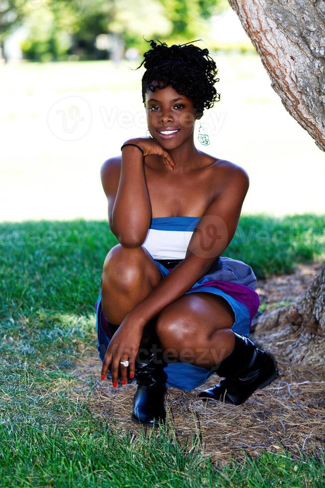 Jeune attrayant africain américain femme squat vers le bas en plein air photo