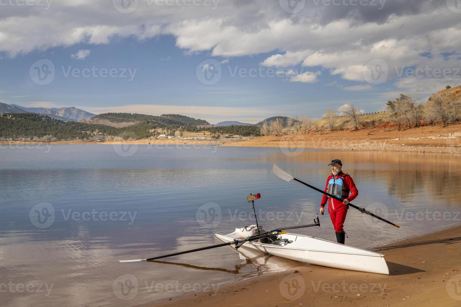 Sénior rameur est gréement le sien aviron coquille sur une rive de charretier Lac dans nord Colorado dans hiver paysage photo