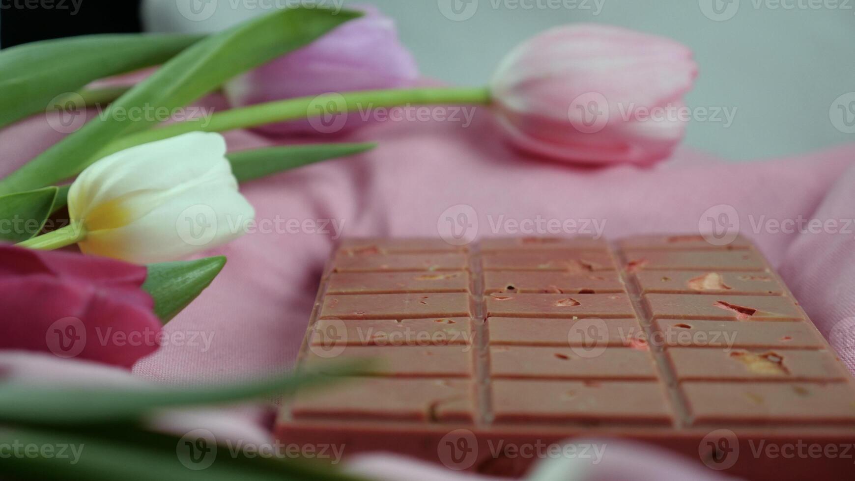 une bar de rose rubis Chocolat avec sublimé lyophilisé des fraises et amandes et printemps tulipe fleurs . une dessert basé sur baies et des noisettes pour international aux femmes jour, Mars 8, de la mère journée photo