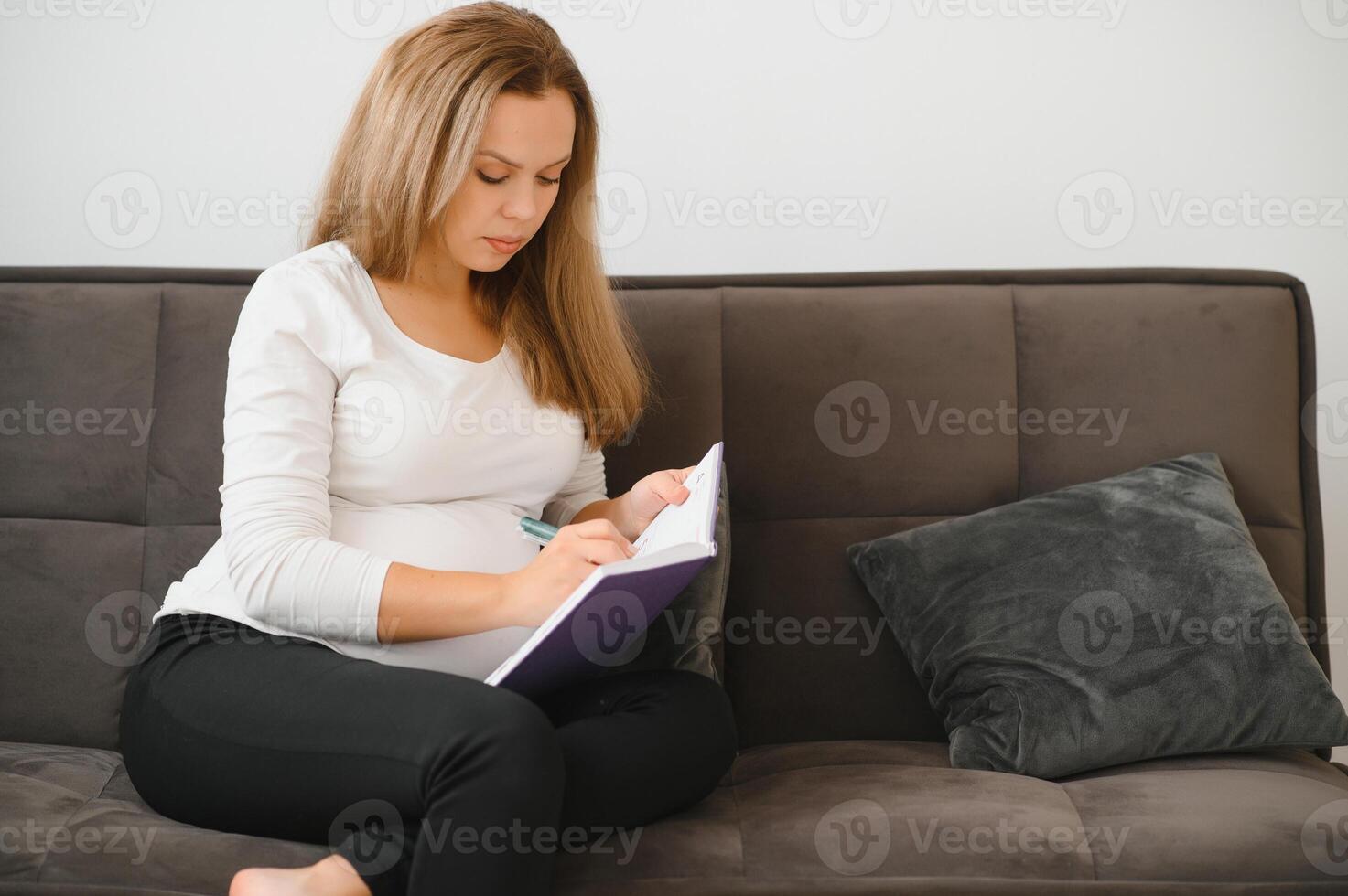 grossesse, gens et attente concept - content Enceinte femme l'écriture à carnet à Accueil photo