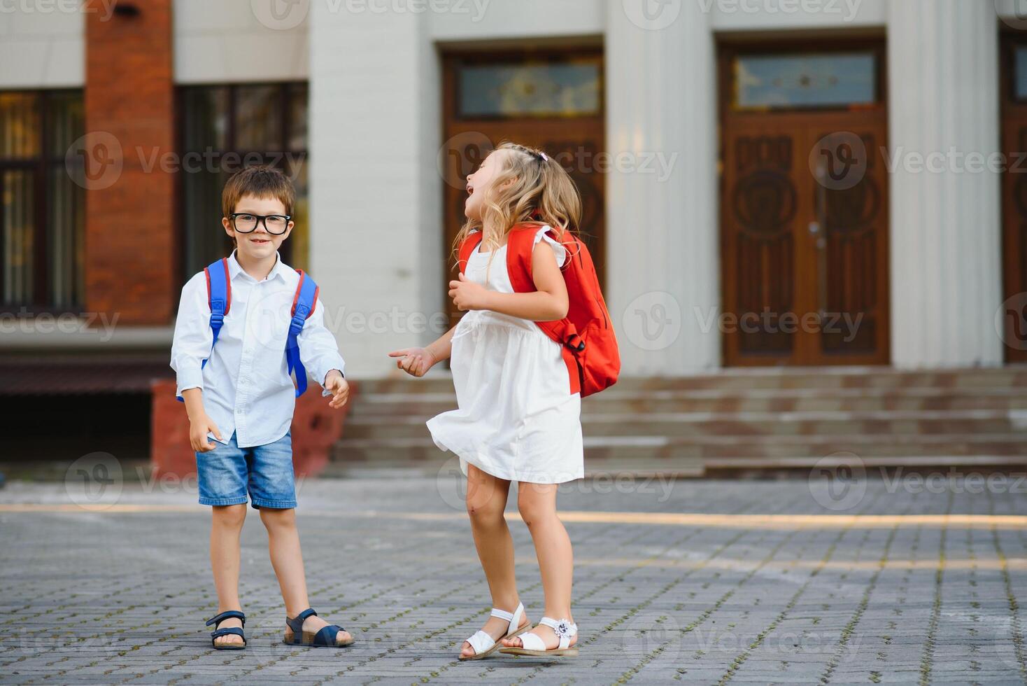content les enfants - garçon et fille avec livres et sacs à dos sur le premier école journée. excité à être retour à école après vacances. plein longueur Extérieur portrait. photo