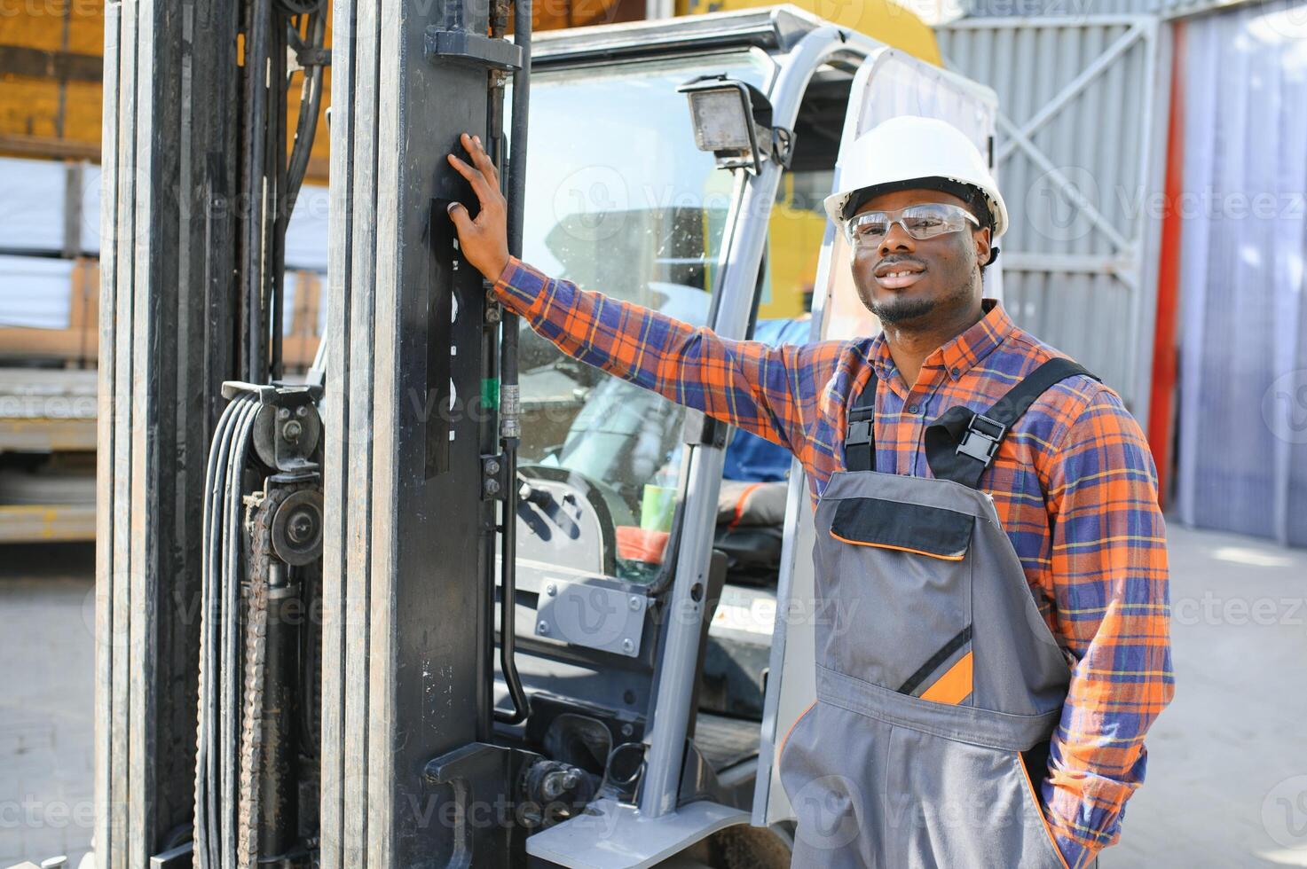 portrait de une content africain américain Masculin ouvrier conduite chariot élévateur à lieu de travail photo