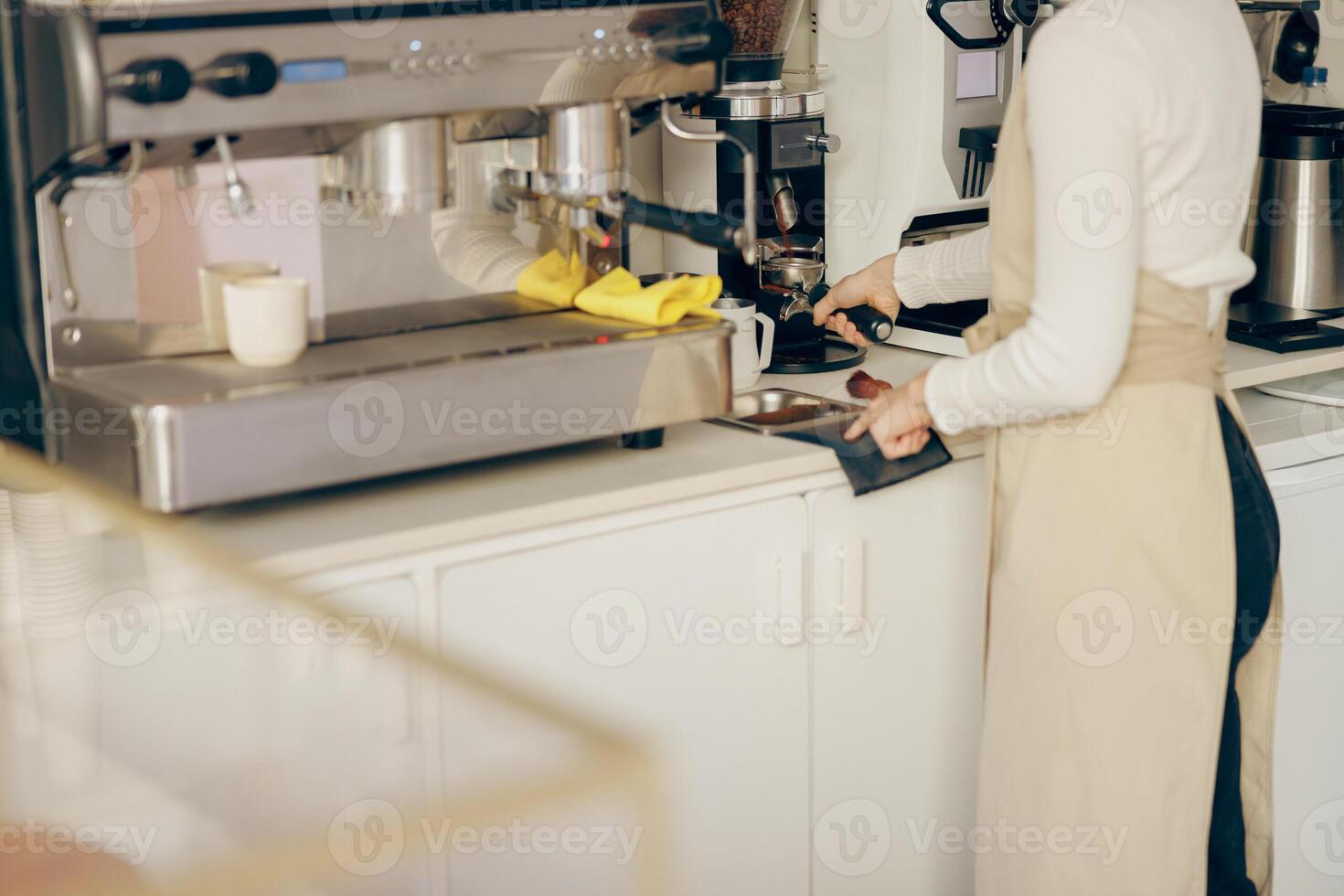proche en haut de femelle barista moudre café haricot avec broyeur machine tandis que travail dans café photo