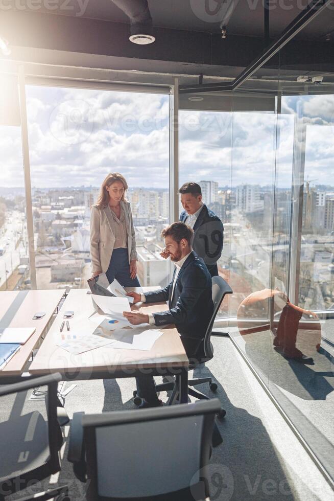 équipe de Jeune les hommes d'affaires travail et communicant ensemble dans moderne Bureau avec panoramique les fenêtres photo