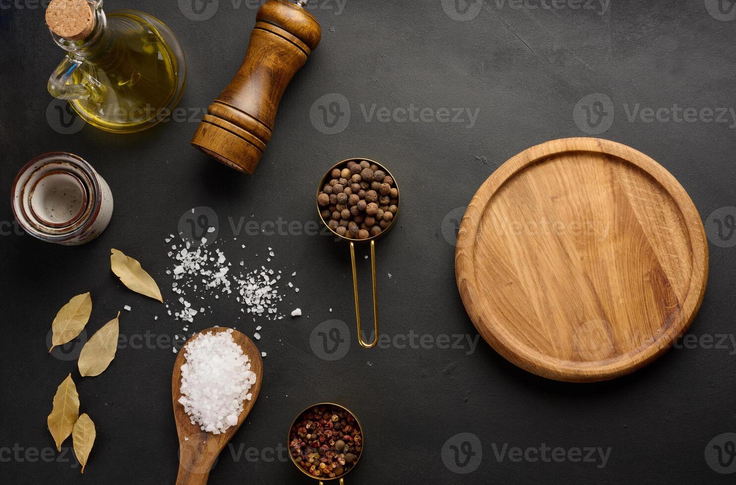 sel, piment de la Jamaïque, poivres et olive pétrole dans une bouteille sur une noir table photo