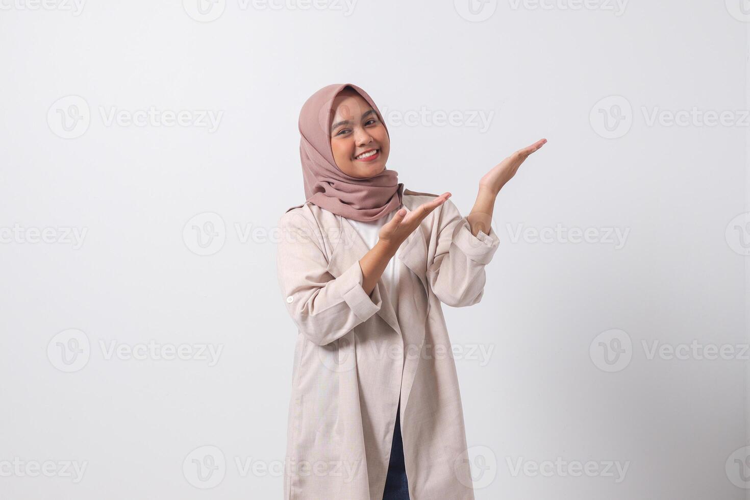 portrait de excité asiatique hijab femme dans décontractée costume montrer du doigt et montrant produit dans sa côté avec doigt. femme d'affaires concept. isolé image sur blanc Contexte photo