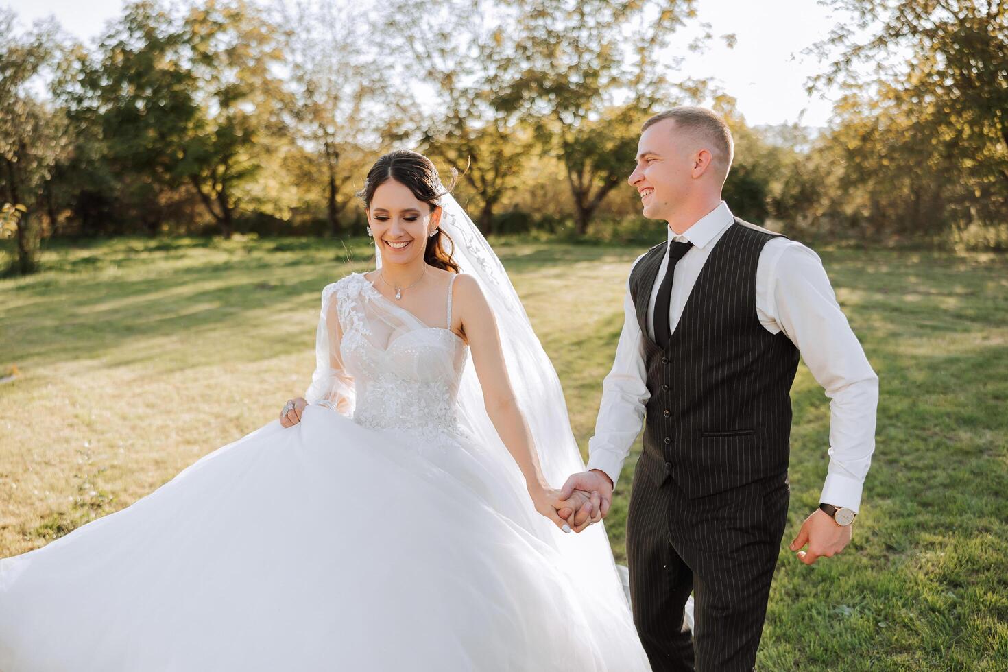 une mariage couple est en marchant dans la nature sur un l'automne journée. content Jeune la mariée et élégant jeune marié en portant mains. une élégant couple de jeunes mariés sur leur mariage journée. photo