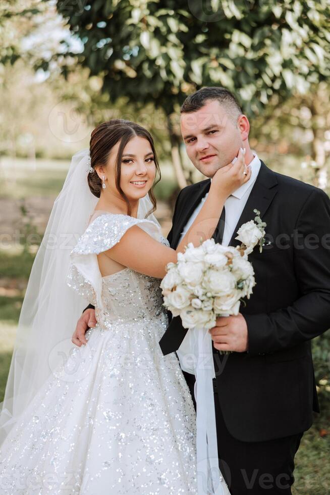 élégant, Jeune jeune marié et magnifique la mariée dans une longue blanc robe et une longue voile avec une bouquet dans leur mains, étreindre dans le parc dans le l'automne la nature. mariage portrait de jeunes mariés. photo