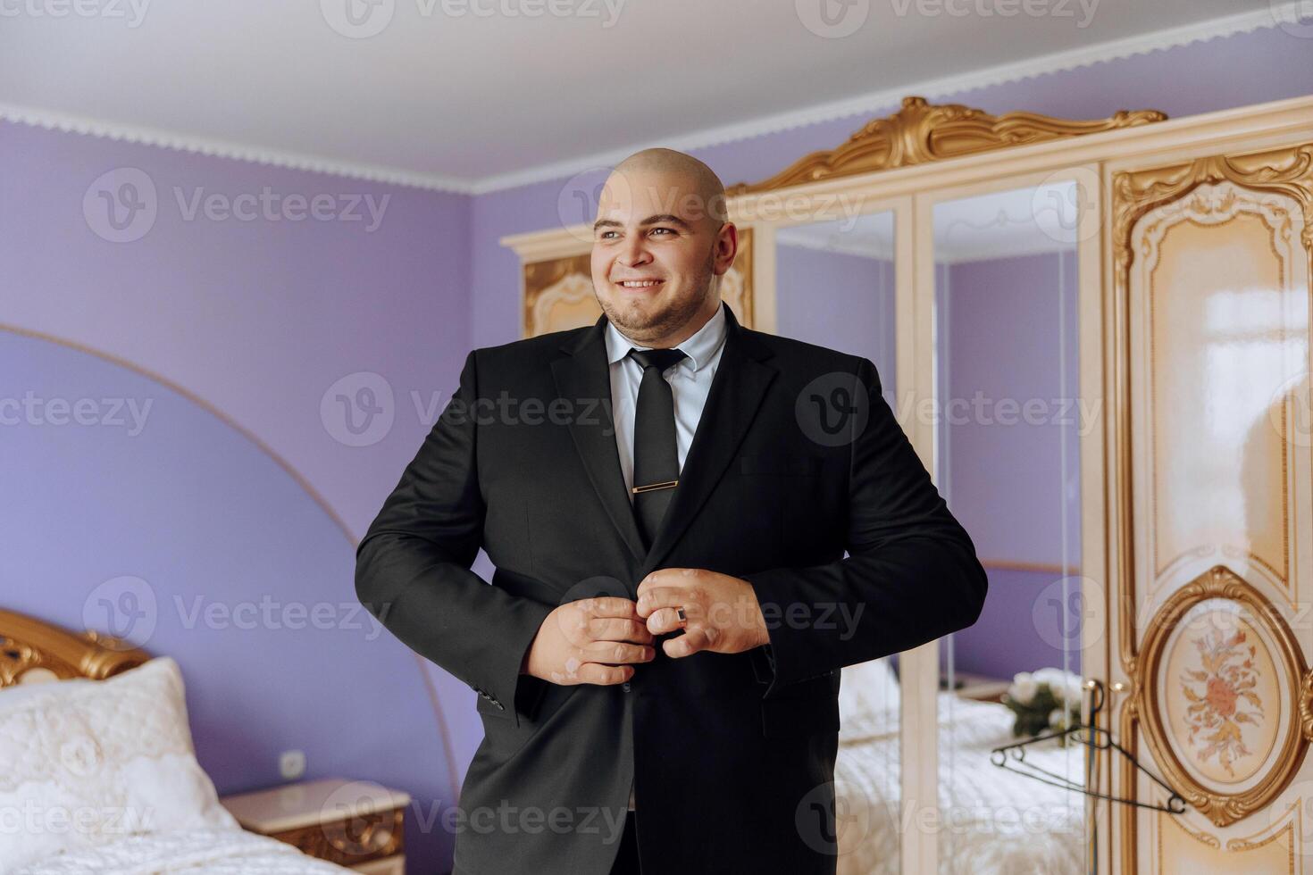 Jeune souriant homme boutonnage en haut le sien veste dans le Matin avant le mariage. fermer de une homme dans une affaires costume. homme d'affaire met sur une costume. une homme attache le boutons sur le sien veste. photo