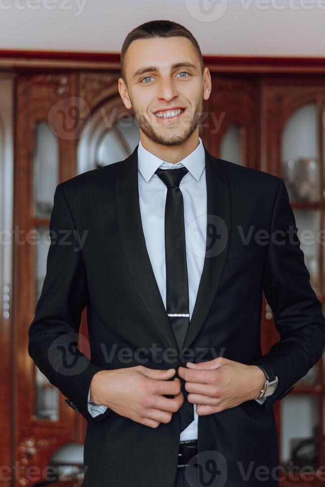 le jeune marié boutons en haut le sien veste le Matin avant le mariage. fermer de une homme dans une affaires costume. homme d'affaire met sur une costume. une homme attache le boutons sur le sien veste. photo