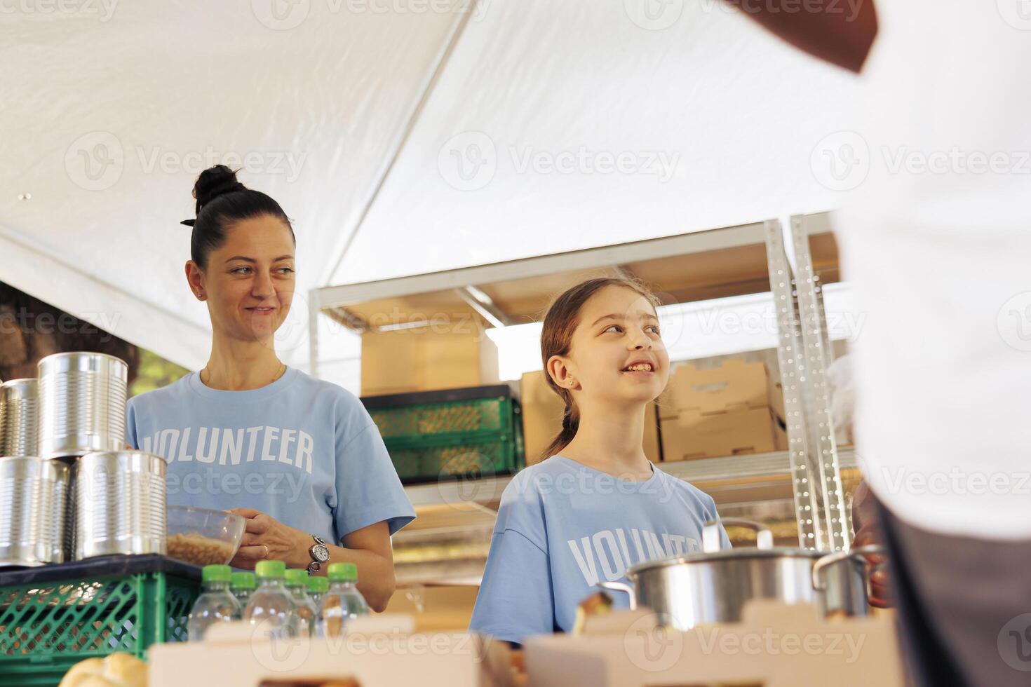 caucasien mère et fille faire du bénévolat à nourriture conduire, fournir gratuit nourriture à le pauvres et nécessiteux. femelle charité ouvriers portion et donnant essentiel articles à sans abri gens et Moins chanceux. photo