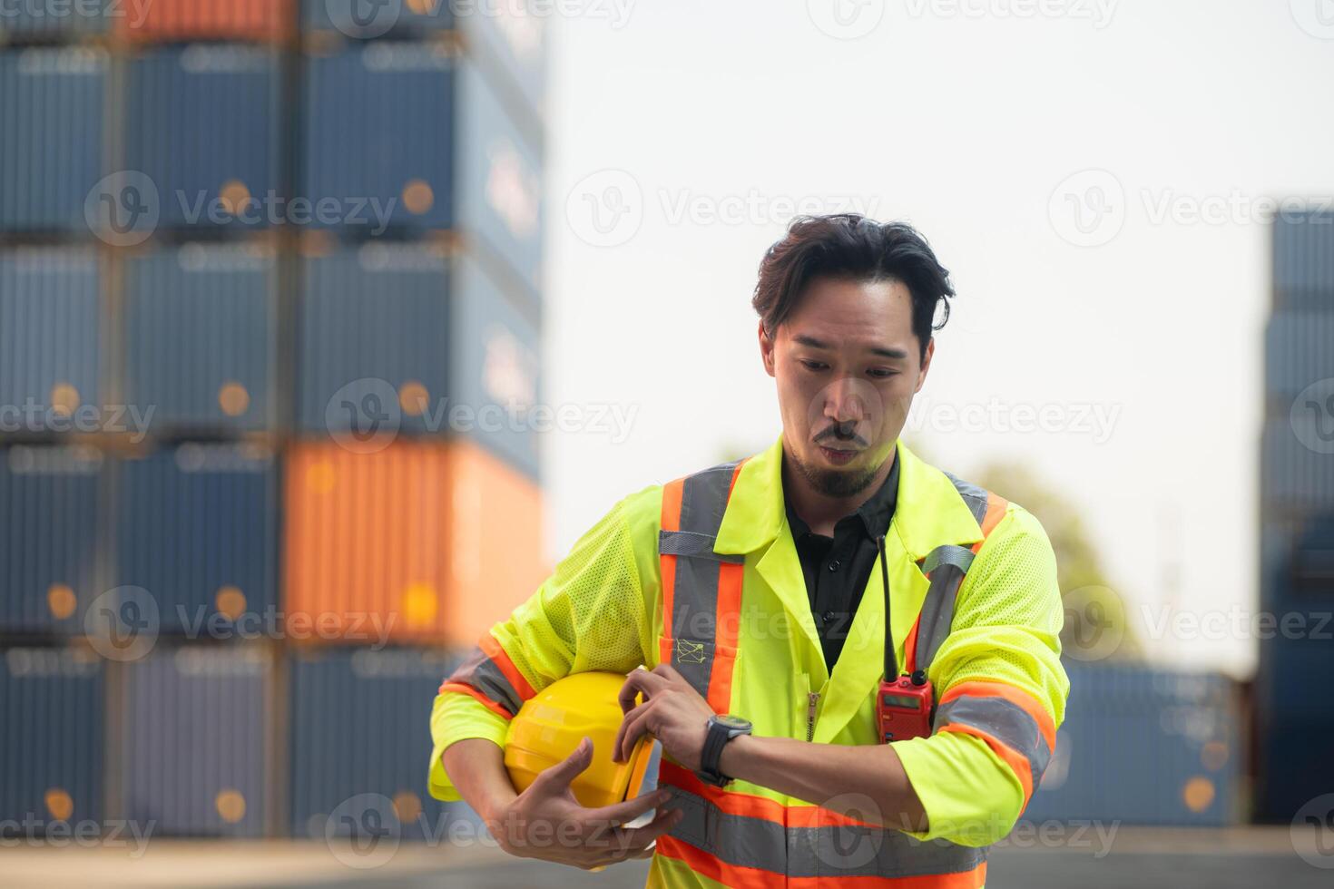 portrait de un asiatique Masculin ouvrier portant une sécurité gilet et difficile chapeau, prise une Pause de travail avec une récipient boîte dans le Contexte photo