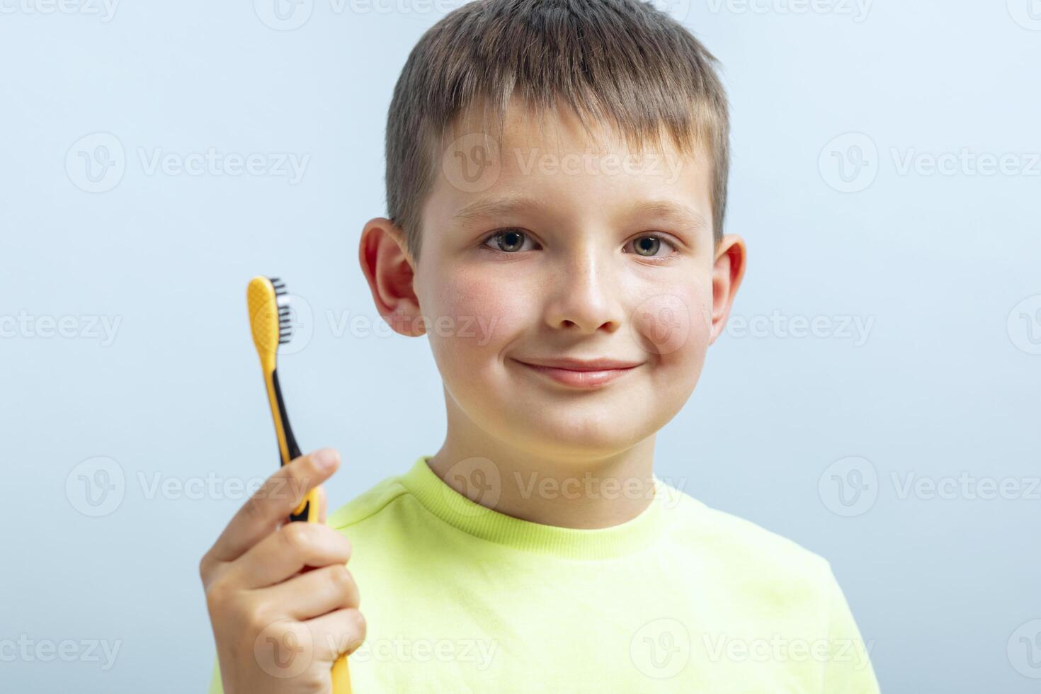 Jeune garçon souriant avec Jaune brosse à dents photo