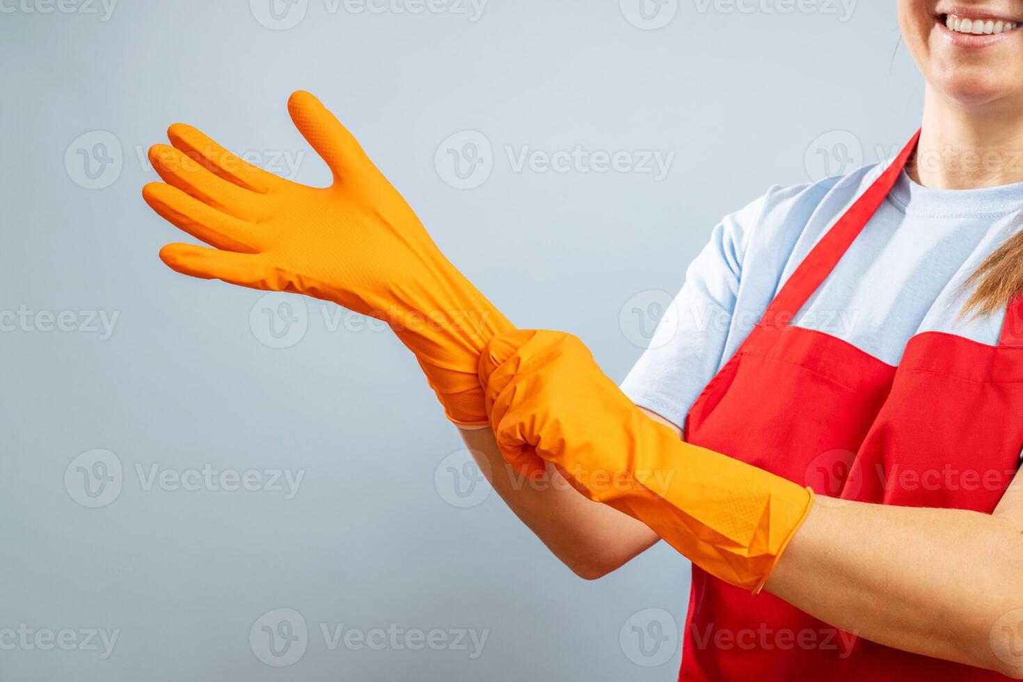 une femme dans rouge tablier en mettant sur protecteur gants sur bleu Contexte photo