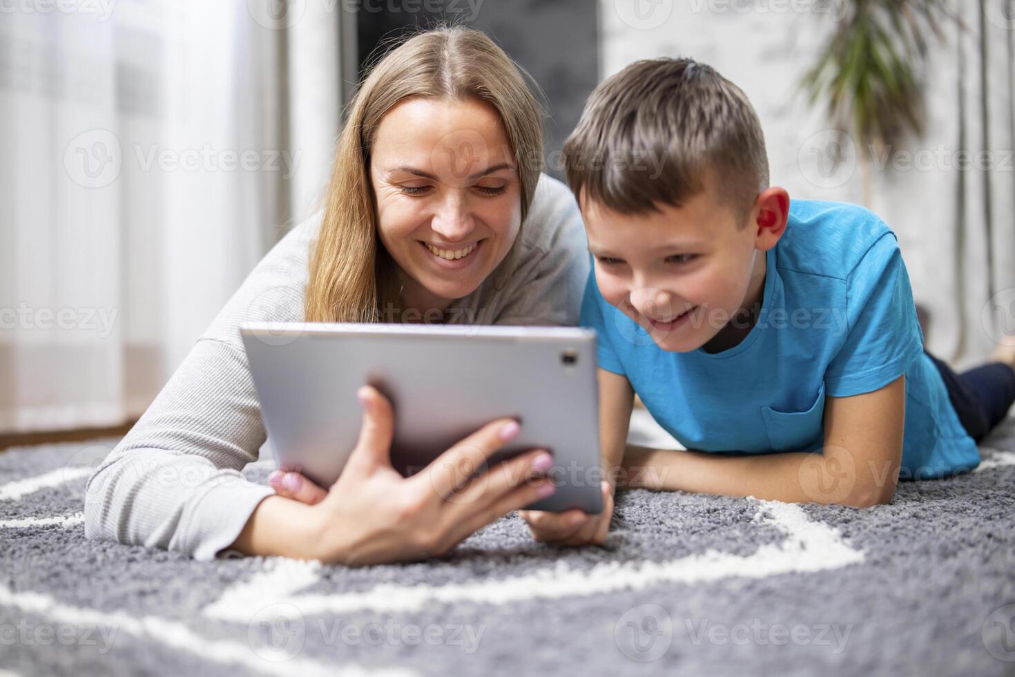 content aimant famille. Jeune mère et sa fils en utilisant tablette mensonge sur tapis photo
