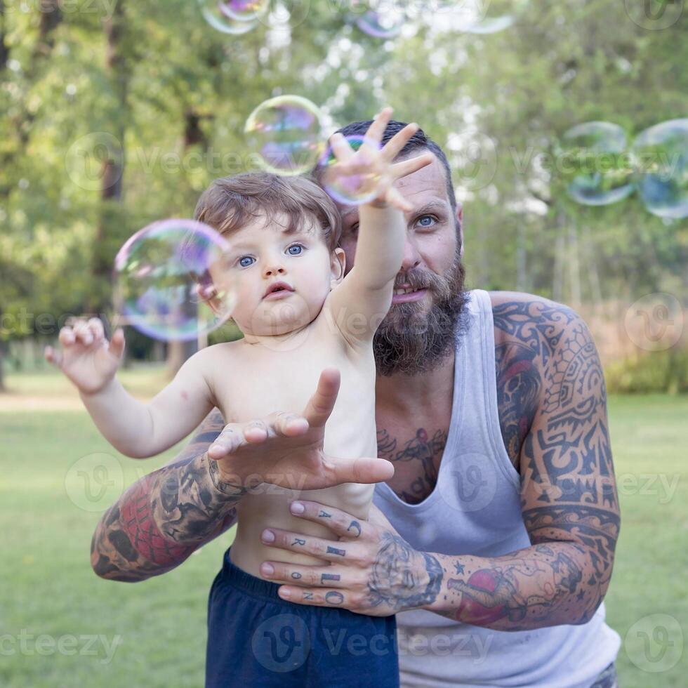 enfant ayant amusement avec le sien papa et essaie à prendre savon bulles photo