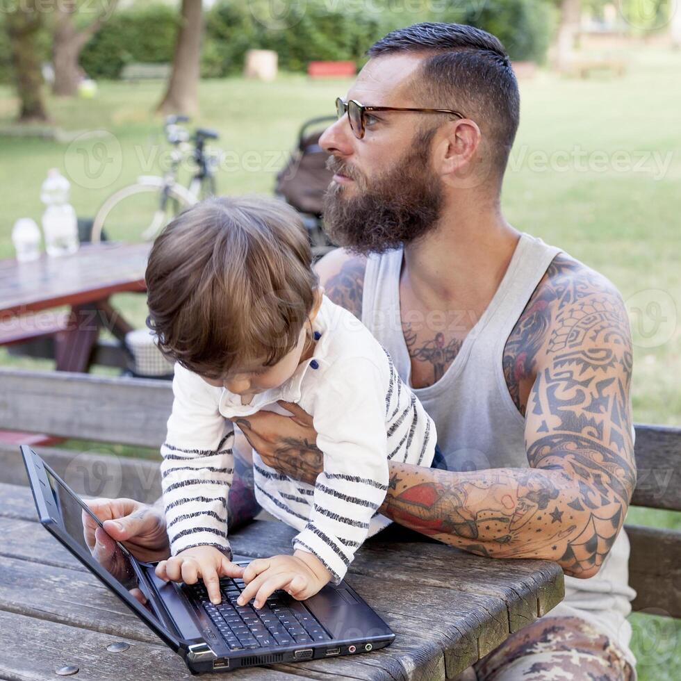 tatoué papa avoir amusement avec le sien fils et portable photo