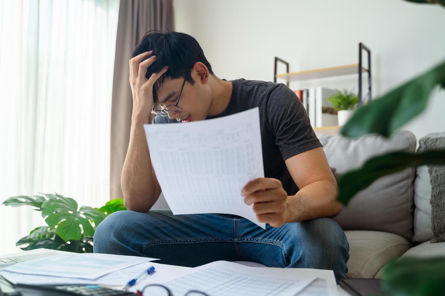 le Hommes est stressé lorsque il voir facture d'achat documents, crédit carte dette, prêts, impôts. photo