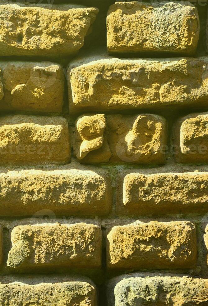 texture de mur vertical de plusieurs rangées de maçonnerie très ancienne en brique rouge. mur de briques brisé et endommagé avec des coins pincés photo