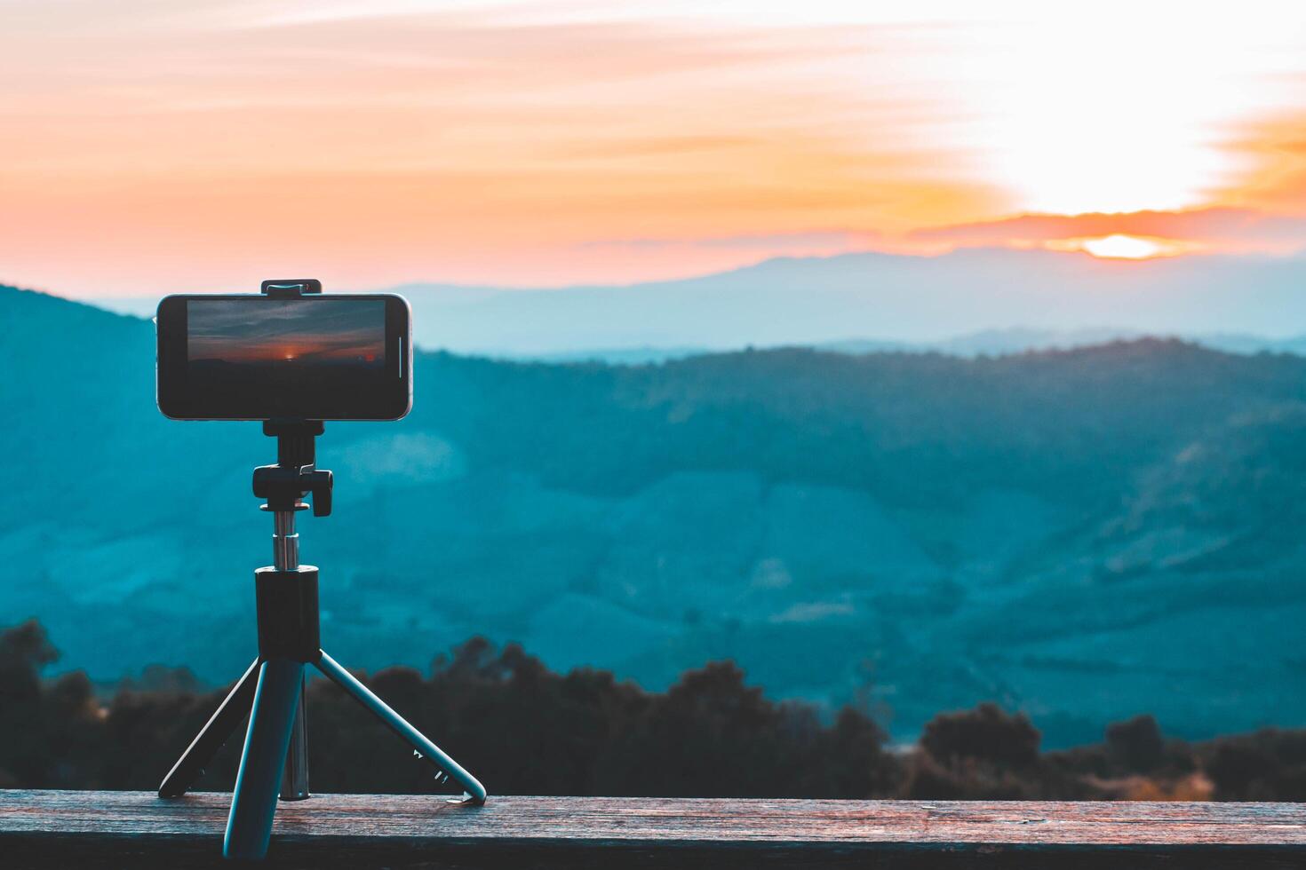 une téléphone intelligent est enregistrement le Soleil réglage plus de une Montagne gamme. photo