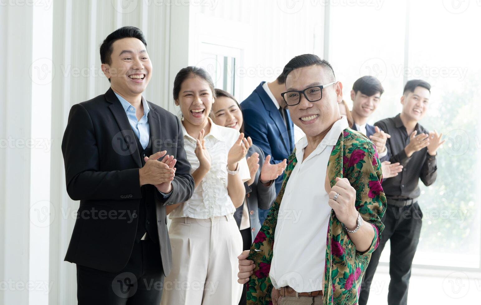 une groupe de gens sont souriant et applaudir, avec un homme dans une floral chemise permanent dehors. scène est content et fête photo