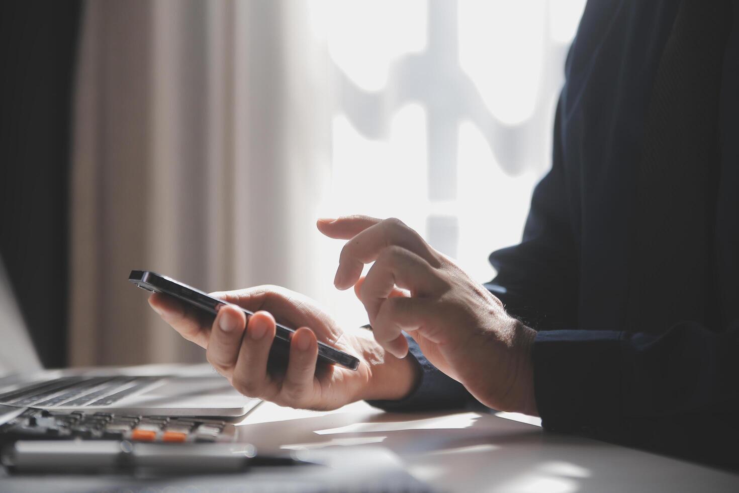 côté vue coup de une homme mains en utilisant intelligent téléphone dans intérieur, arrière vue de affaires homme mains occupé en utilisant cellule téléphone à Bureau bureau, Jeune Masculin étudiant dactylographie sur téléphone séance à en bois tableau, éclater photo