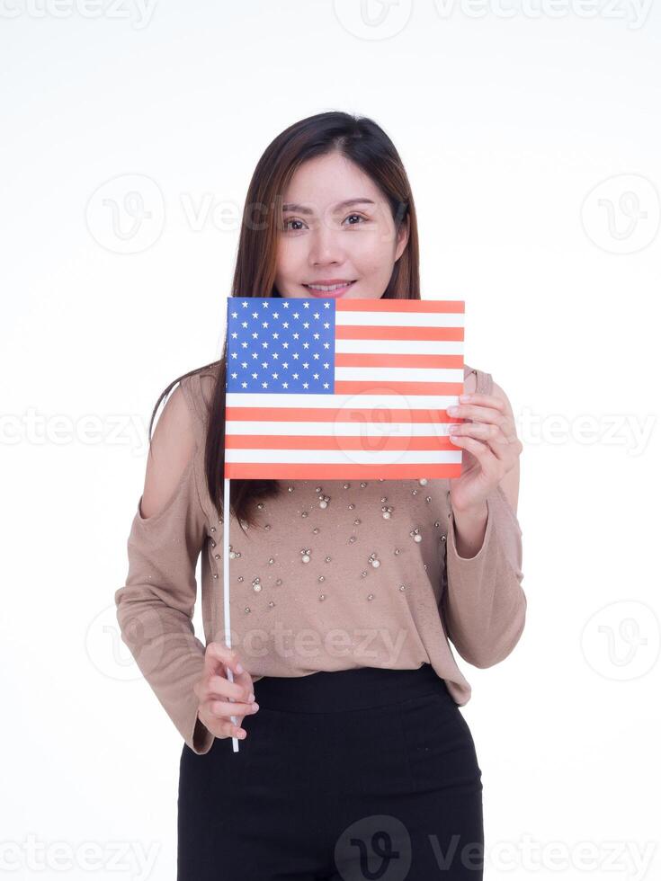 Jeune femme en portant le nous drapeau, souriant et à la recherche à le caméra avec une blanc Contexte. espace pour texte. 4e de juillet. célébrer américain nationale journée. la main d'oeuvre journée. indépendance journée photo