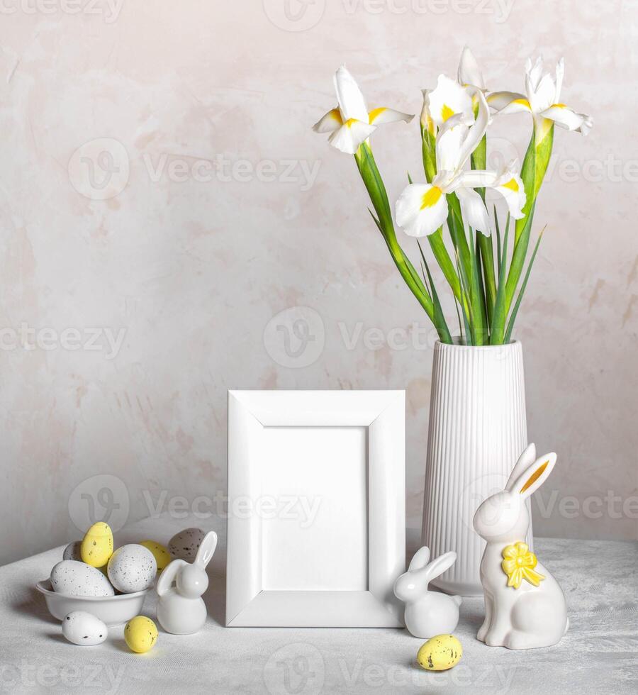 Pâques blanc encore la vie avec Vide cadre, décoratif œufs, lapins, vase avec iris fleurs sur tableau. photo