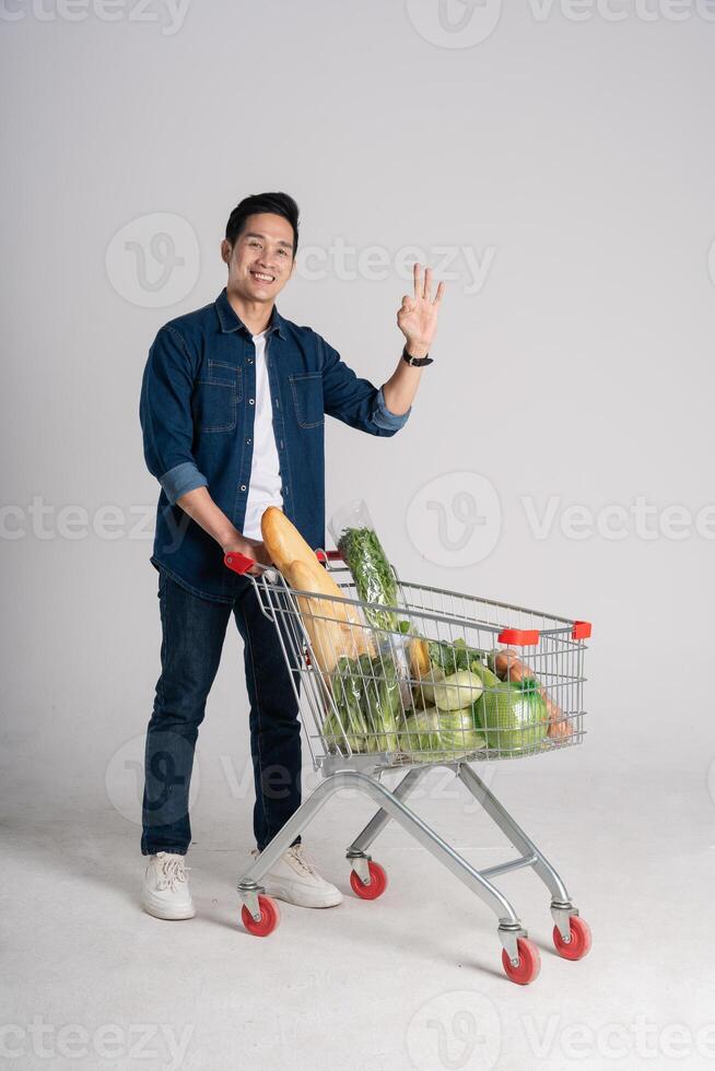 content souriant homme pousser supermarché Chariot isolé sur blanc Contexte photo